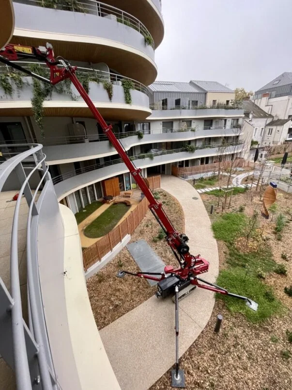 Mini grue HOEFLON vendue par PRO2MAT, utilisée pour le levage sur un chantier résidentiel moderne